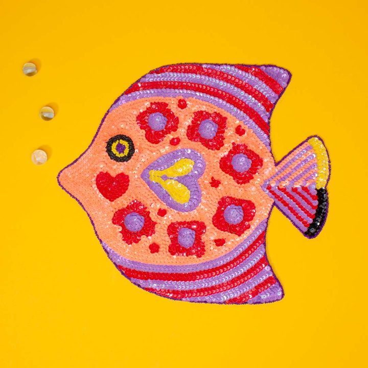 Ein handgemachter Pailletten-Aufnäher aus Mexiko, der aussieht wie ein farbenfroher tropischer Diskusfisch und von der Künstlerin Margaux Carpentier entworfen wurde.