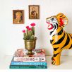 Stillleben mit einem kleinen Kaktus, der als skulpturales Element dient, um einen Stapel Bücher mit einer grossen Tonfigur eines Tigers optisch zu verbinden.